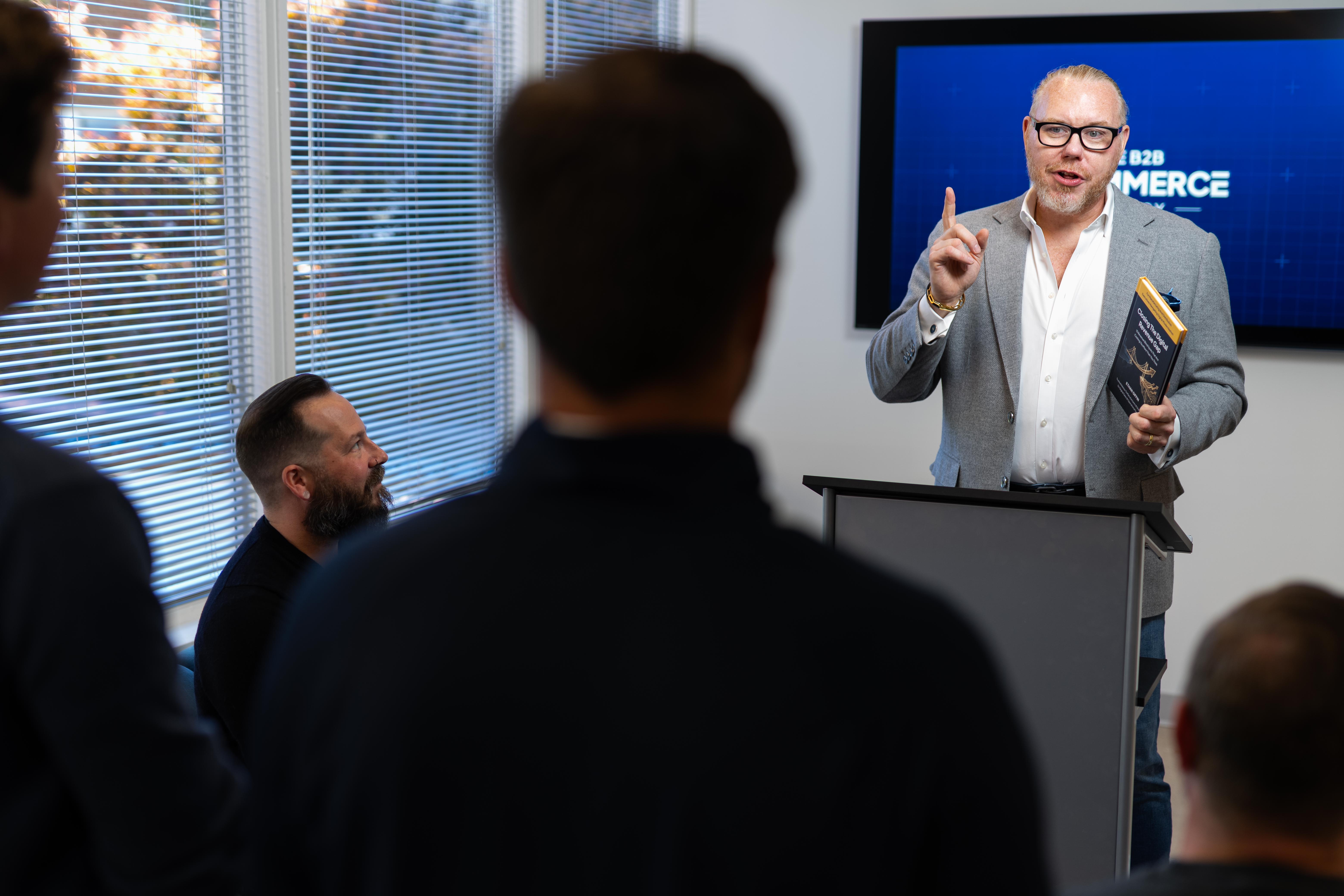 Ethan Giffin speaking to a group, holding his book